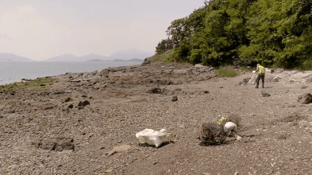 Person cleaning a rocky beach