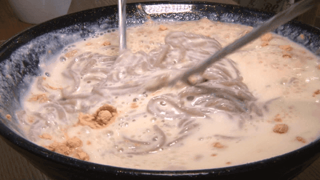 콩가루가 뿌려진 콩국수가 젓가락으로 섞이는 장면