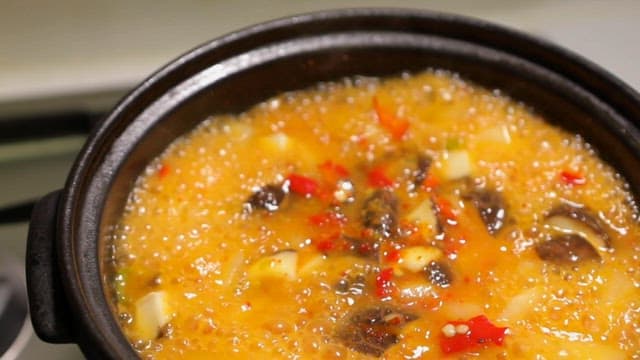 Boiling soybean paste soup in a black pot on a stove