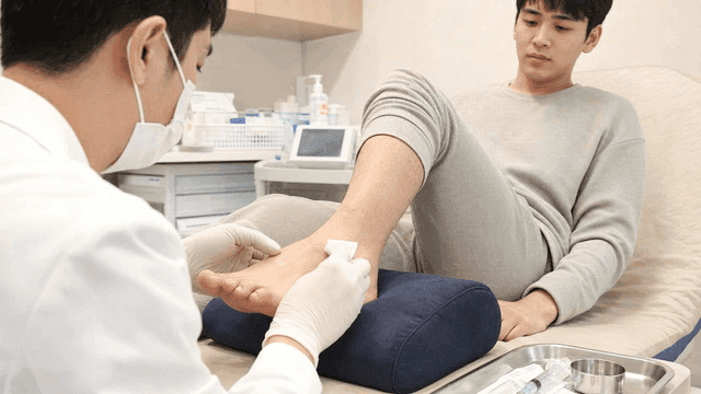 Doctor disinfecting patient's foot at hospital