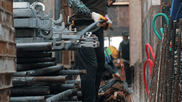 Workers handling metal pipes at a construction site