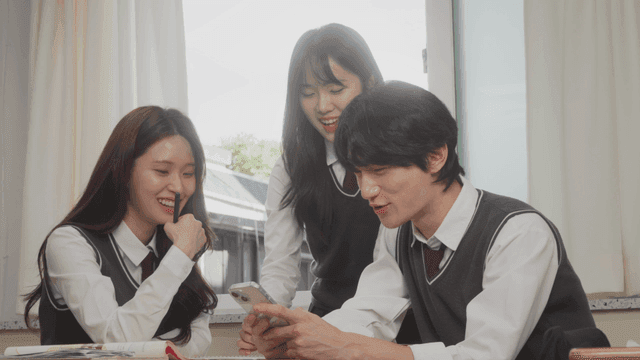 Students laughing while looking at a smartphone together