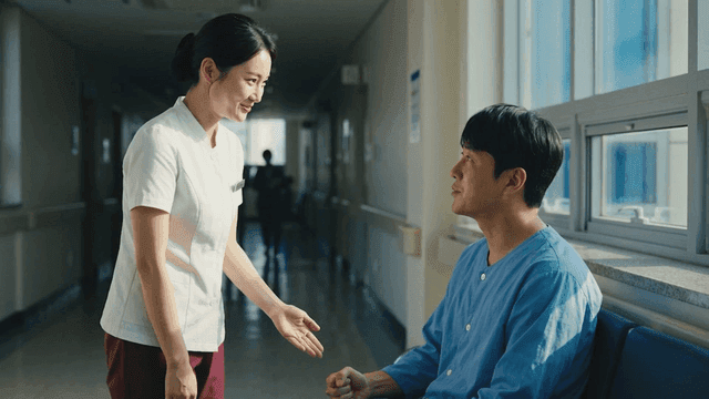 A nurse talking to a patient in a hospital corridor