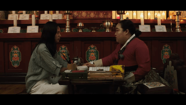 Shaman and a woman conversing in a fortune teller's shop