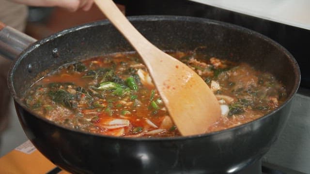 매콤하고 뜨거운 곤드레 찌개에 다진 마늘을 넣기