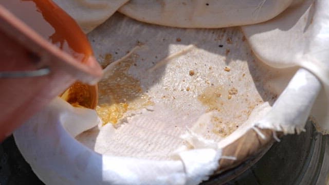 Filtering Soybean Paste over the White Cloth over a Pot