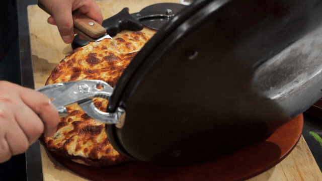 서빙보드 위로 옮겨지는 갓 구운 피자