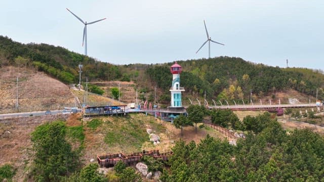 Lighthouse and wind turbines on a hill