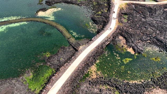 Coastal path with volcanic rocks and turquoise sea