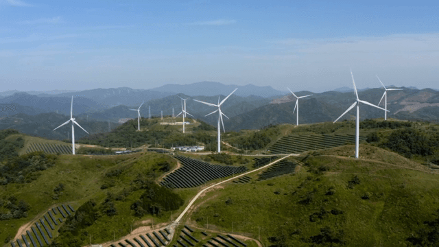 푸른 하늘 아래 녹색 산악 지역의 풍력 터빈