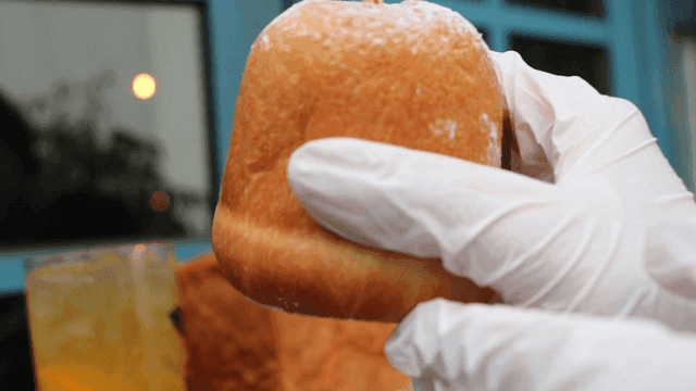 A gloved hand holding a piece of bread