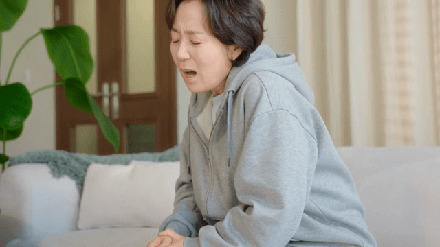 무릎을 잡고 불편해하는 여성