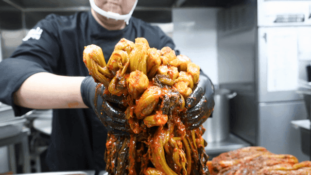 Chef lifting freshly made gatgimchi in kitchen