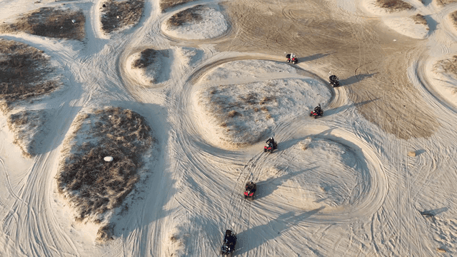 ATVs driving on sandy terrain by the sea