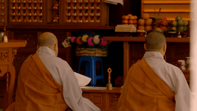 Backs of monks chanting in front of altar