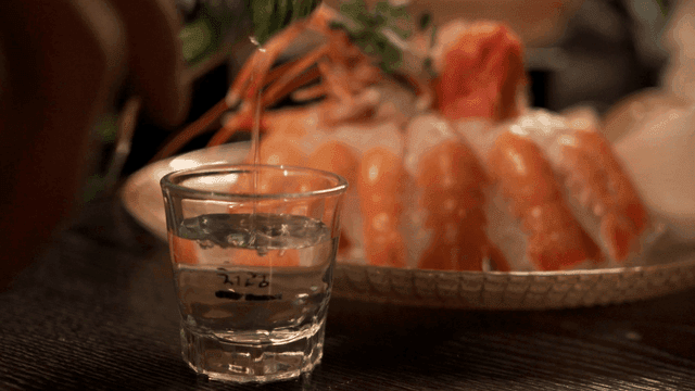 Scene of pouring soju into soju glass next to raw shrimp