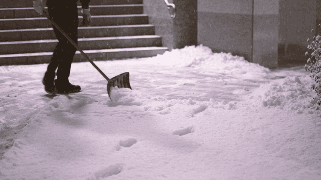Person clearing snow in front of house