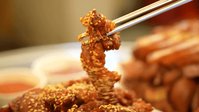 Chopsticks picking up spicy pig's trotters sprinkled with sesame seeds