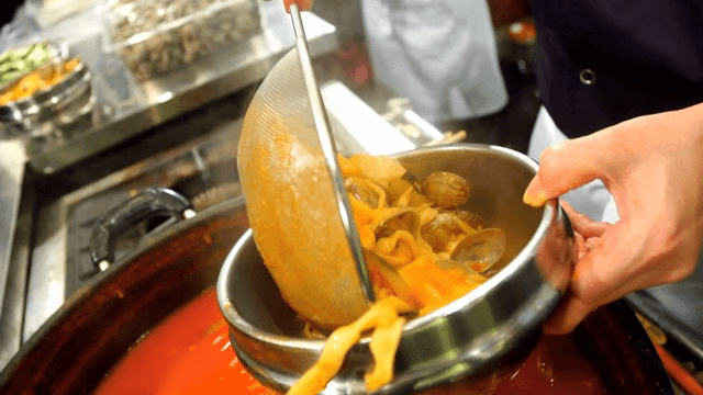 그릇에 옮겨 담는 바지락과 야채가 들어간 얼큰 칼국수