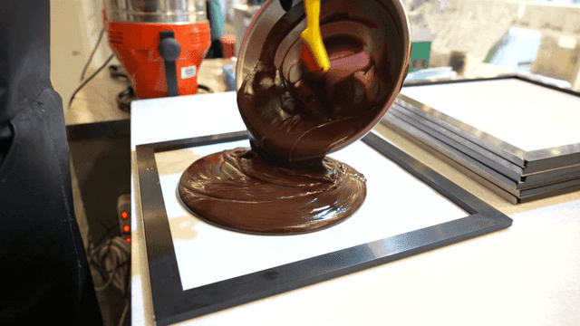 Pouring melted chocolate onto a tray