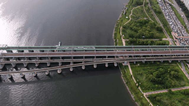Trains crossing bridge over river and surrounding greenery