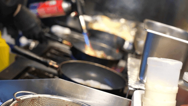 A busy kitchen with flames and sauces