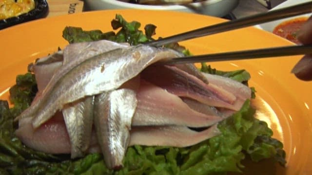 Sliced raw scaled sardine dipped in red chili-pepper paste with vinegar at a sushi restaurant