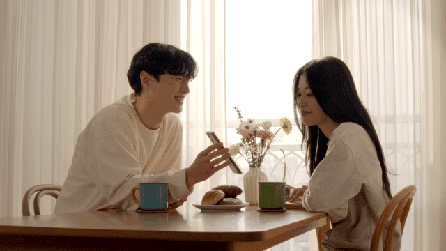 아침식사가 있는 식탁에서 스마트폰으로 사진을 찍는 커플