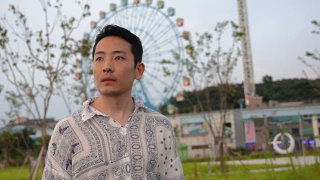 관람차 옆 공원을 걷는 남자