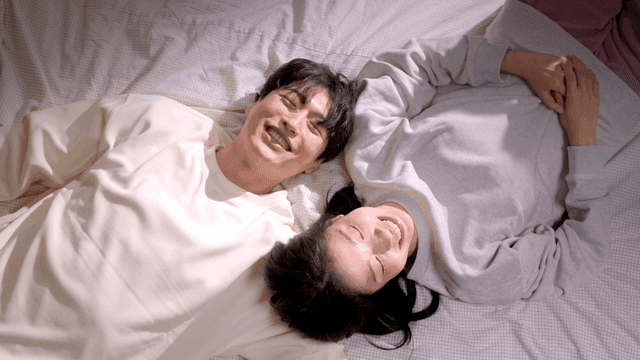 Couple playfully smiling on bed