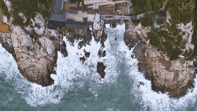 Waves striking the coastal cliff with a seaside temple