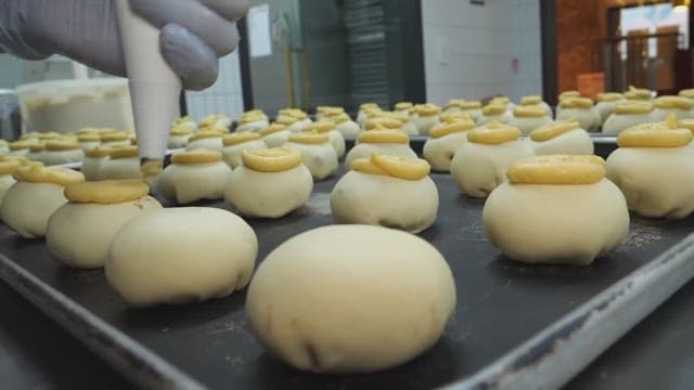 Pastry chef applying cream to dough in the kitchen