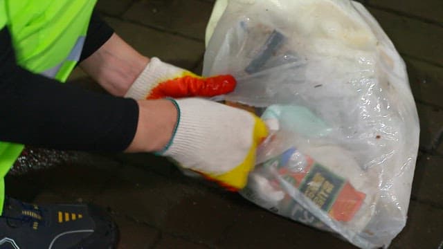 Street cleaner in a reflective vest examining garbage