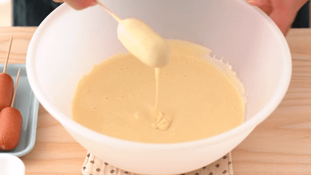 가루를 묻힌 소시지에 반죽을 입히는 장면