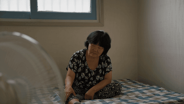 실내에서 침대에 앉아 있는 노인 여성