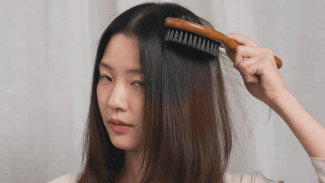 Woman brushing her long hair indoors