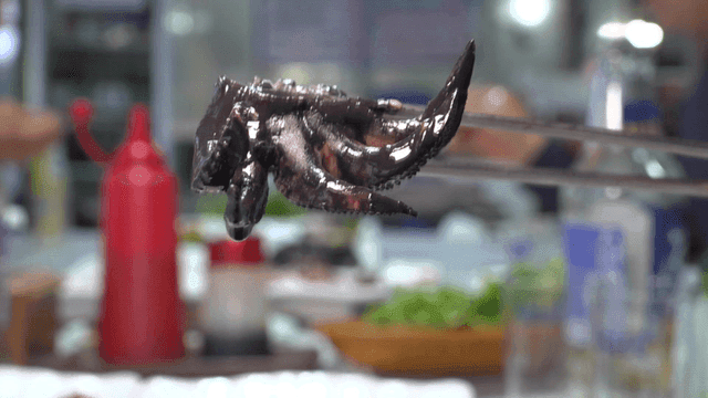 Ink-soaked cuttlefish dish lifted with chopsticks