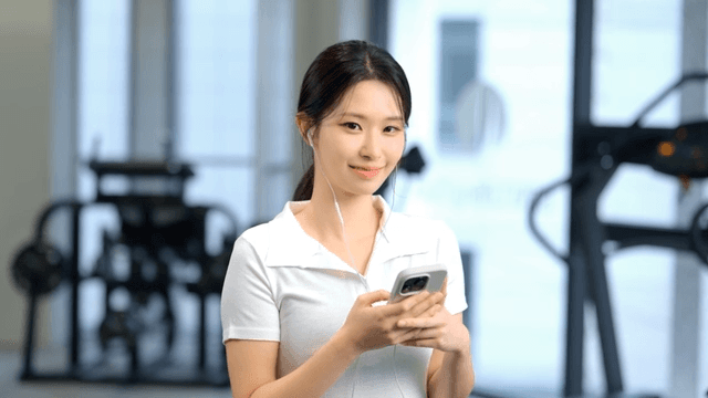 Woman using smartphone with earphones at gym