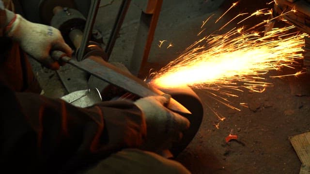 Worker sharpening a knife with sparks