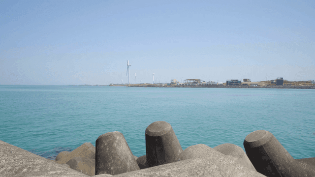 Coastal landscape with wind turbines and breakwaters