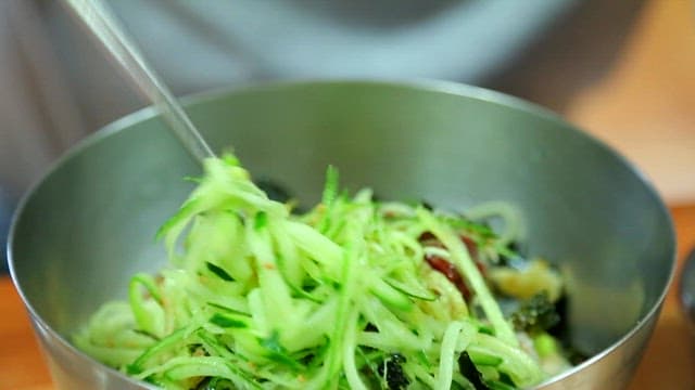 Mixing cold raw fish soup with fresh vegetables