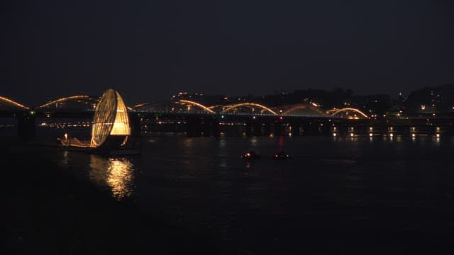 Illuminated bridge and Han River with boats at night