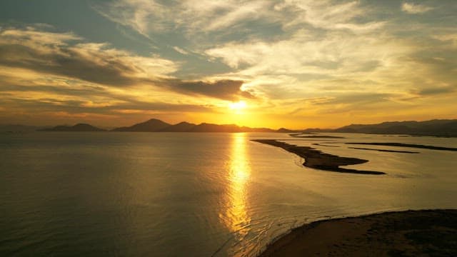 Sunset over a calm sea with distant mountains