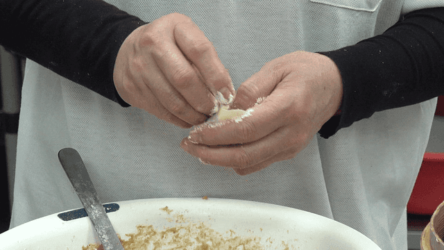 Hands making dumplings with filling