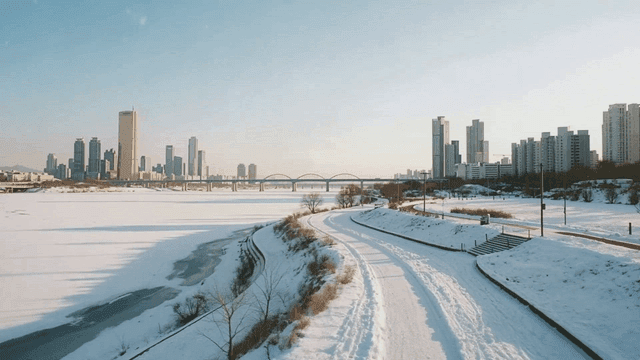 Snow-covered riverside with city skyline
