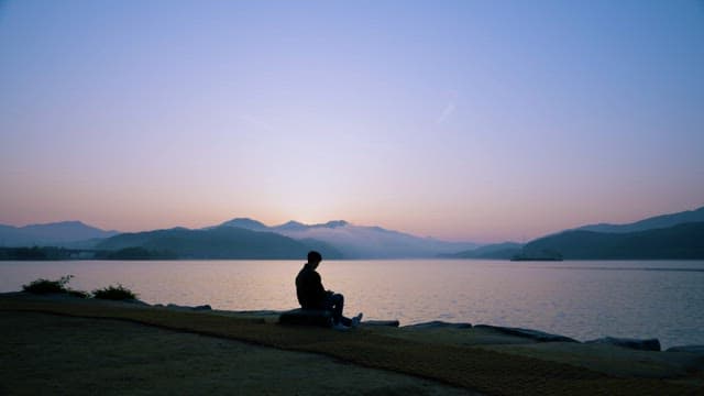 Serene lakeside sunrise with a solitary figure