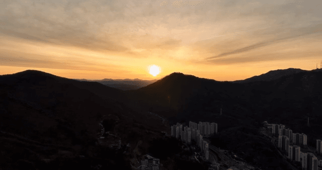 산과 도시 풍경 위로 지는 해