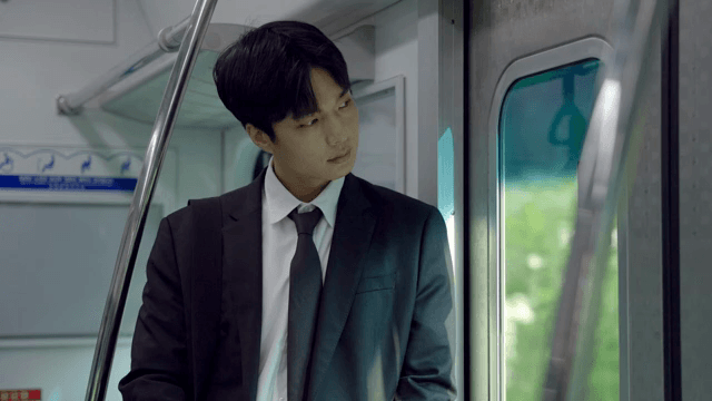 창문 밖 풍경을 구경하며 지하철을 타고 이동하는 직장인 남성
