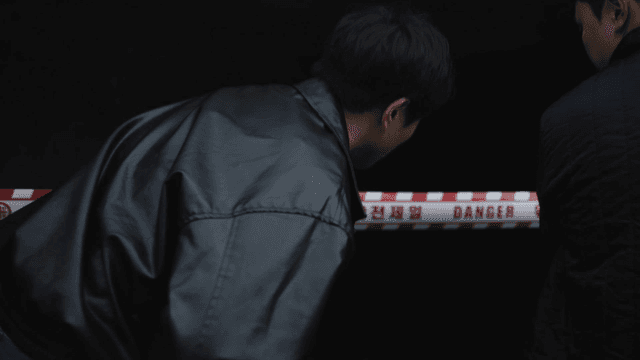 Man's back as he walks into dark area with caution tape.