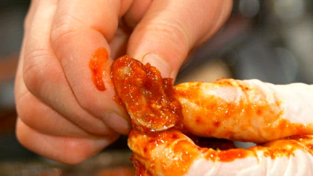 Gloved hands handling spicy marinated crab